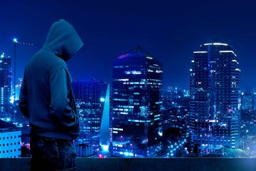 achmad - Computer hacker silhouette of hooded man standing on the top of the building at night.